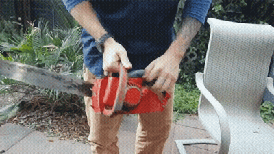 A Man With A Tattoo On His Arm Is Using A Chainsaw GIF