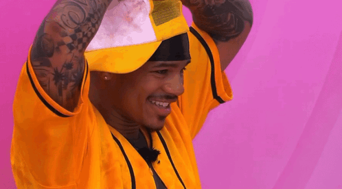 A Man With A Tattoo On His Arm Is Wearing A Yellow Shirt And A White Hat GIF