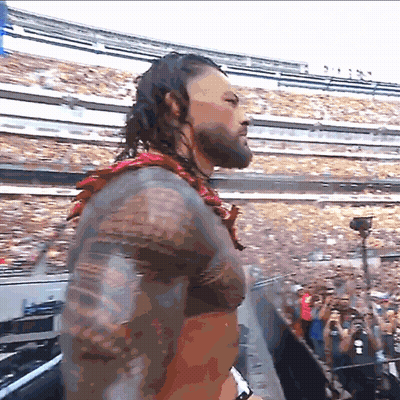 A Man With A Tattoo On His Arm Stands In Front Of A Crowd GIF
