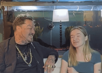 A Man With A Tattoo On His Arm Talks To A Girl GIF