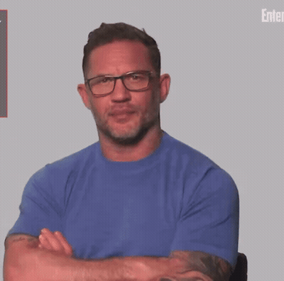 A Man With A Tattoo On His Arm Wearing A Blue Shirt And A Watch . GIF