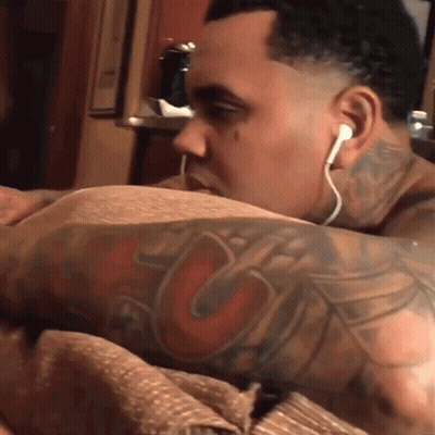 A Man With A Tattoo On His Arm Wearing Ear Buds GIF