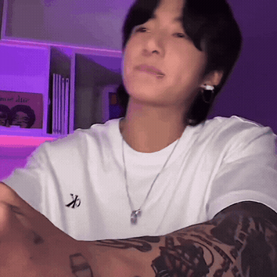 A Man With A Tattoo On His Arm Wears A White Shirt With The Letter X On The Front GIF