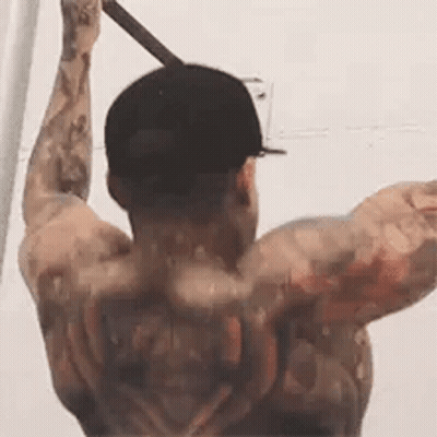 A Man With A Tattoo On His Back Is Doing Pull Ups On A Bar . GIF
