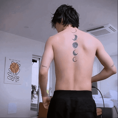 A Man With A Tattoo On His Back Is Standing In Front Of A Framed Matisse Painting GIF
