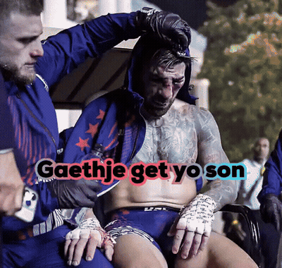 A Man With A Tattoo On His Chest Is Being Helped By A Man In A Blue Jacket With The Words Gaethje Get Yo Son GIF