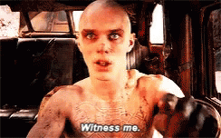 A Man With A Tattoo On His Chest Is Sitting In A Car And Saying Witness Me . GIF