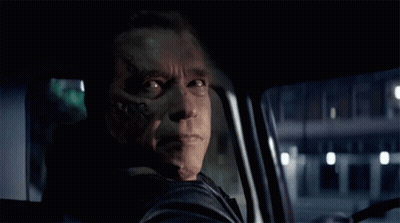 a man with a tattoo on his face is smiling while driving a car