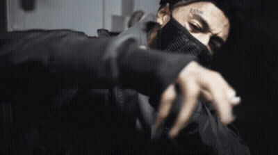 A Man With A Tattoo On His Face Is Wearing A Mask And A Ring On His Finger . GIF