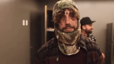A Man With A Tattoo On His Face Wears A Camo Hood GIF
