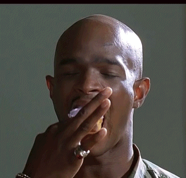 A Man With A Tattoo On His Forehead Is Holding A Donut In His Hand GIF