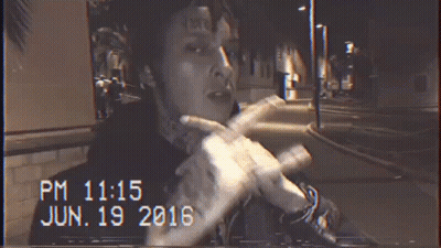 A Man With A Tattoo On His Forehead Is Smoking A Cigarette At Night GIF