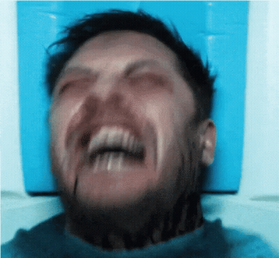 A Man With A Tattoo On His Neck Is Making A Funny Face With His Mouth Open . GIF