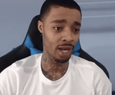 A Man With A Tattoo On His Neck Is Sitting In A Chair And Looking At The Camera . GIF