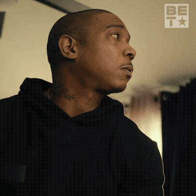 A Man With A Tattoo On His Neck Looks To The Side With A Be T Logo Behind Him GIF