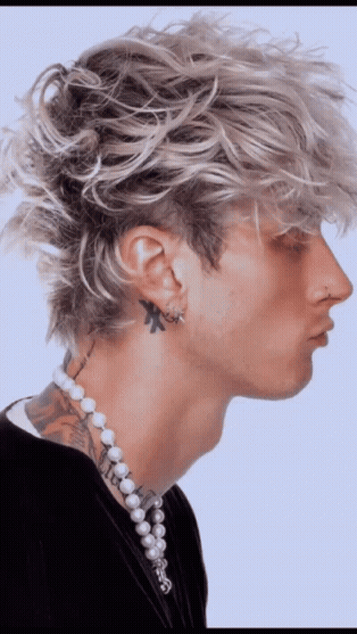 A Man With A Tattoo On His Neck Wearing Pearls And Earrings GIF