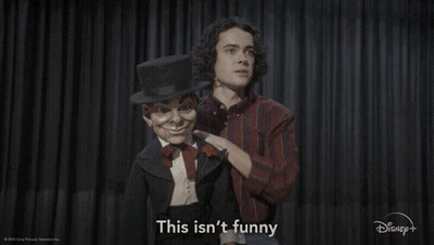 A Man With A Top Hat Is Standing Next To A Puppet That Says This Isn 'T Funny GIF