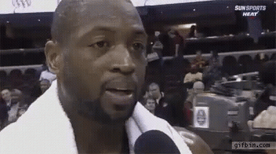 A Man With A Towel Around His Neck Is Talking Into A Microphone At A Sun Sports Heat Game . GIF