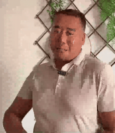 A Man With A Towel Around His Neck Looks At The Camera GIF
