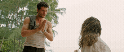 A Man With A Towel Around His Shoulder Talks To A Woman GIF