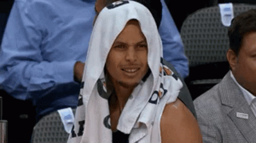 A Man With A Towel Wrapped Around His Head Is Sitting In The Stands At A Basketball Game . GIF