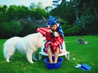 A Man With A Towel Wrapped Around His Head Sits In A Chair With A Dog GIF