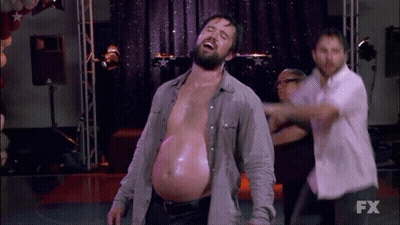 A Man With A Very Large Belly Is Dancing On A Stage In Front Of A Fx Logo . GIF