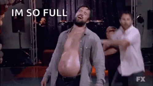 A Man With A Very Large Belly Is Dancing On A Stage With Other People . GIF