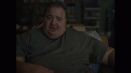 A Man With A Very Large Belly Is Sitting At A Table And Smiling . GIF