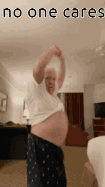 A Man With A Very Large Belly Is Standing In A Living Room With The Words No One Cares Written On The Bottom GIF