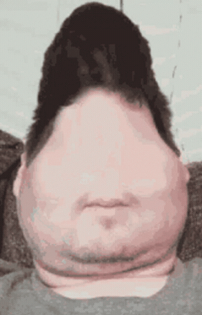 A Man With A Very Large Head And Neck Is Sitting On A Couch And Making A Funny Face . GIF