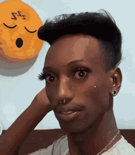 A Man With A Very Short Haircut Is Making A Funny Face In Front Of A Yellow Smiley Face . GIF