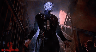A Man With A Very Spiky Head Is Standing In A Dark Room Holding A Knife . GIF