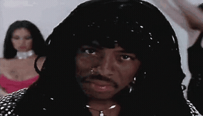 A Man With A Wig And A Mustache Is Standing In Front Of A Woman In A Pink Dress . GIF