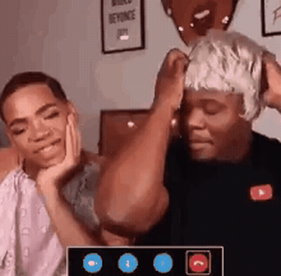 A Man With A Wig On His Head Is Sitting Next To A Woman . GIF