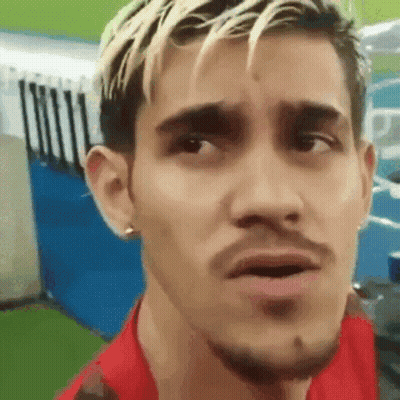 A Man With Blonde Hair And A Beard Is Making A Funny Face While Wearing A Red Shirt . GIF