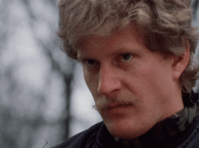 A Man With Blonde Hair And A Mustache Is Looking At The Camera GIF