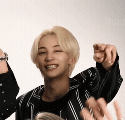 A Man With Blonde Hair And Braces Is Pointing At The Camera . GIF