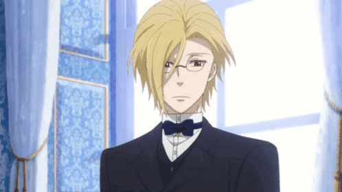 A Man With Blonde Hair And Glasses Is Wearing A Suit And Bow Tie GIF