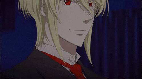 A Man With Blonde Hair And Red Eyes Is Wearing A Black Suit And Tie GIF