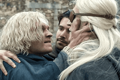 A Man With Blonde Hair Is Hugging Another Man And A Woman GIF