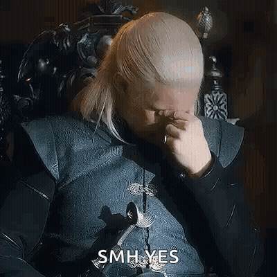 A Man With Blonde Hair Is Sitting In A Chair And Rubbing His Eyes . GIF