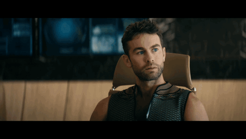A Man With Blonde Hair Is Sitting In Front Of A Large Window GIF