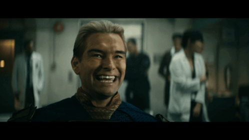 A Man With Blonde Hair Is Smiling In A Room GIF