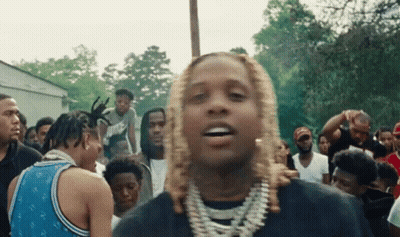 A Man With Blonde Hair Is Standing In Front Of A Crowd Of Men . GIF