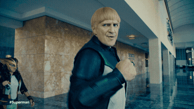 A Man With Blonde Hair Is Walking In A Hallway With The Hashtag #Superman GIF