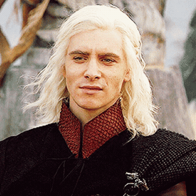 A Man With Blonde Hair Is Wearing A Black Cape And Red Collar GIF