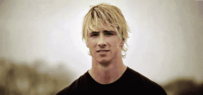 A Man With Blonde Hair Is Wearing A Black Shirt And Looking At The Camera GIF