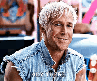 A Man With Blonde Hair Is Wearing A Denim Vest And Smiling While Saying Hey There . GIF