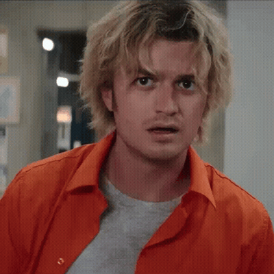 A Man With Blonde Hair Is Wearing An Orange Shirt And A Grey T-Shirt GIF